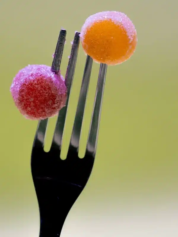 Close-up of two colorful sugar-coated gummies on a fork